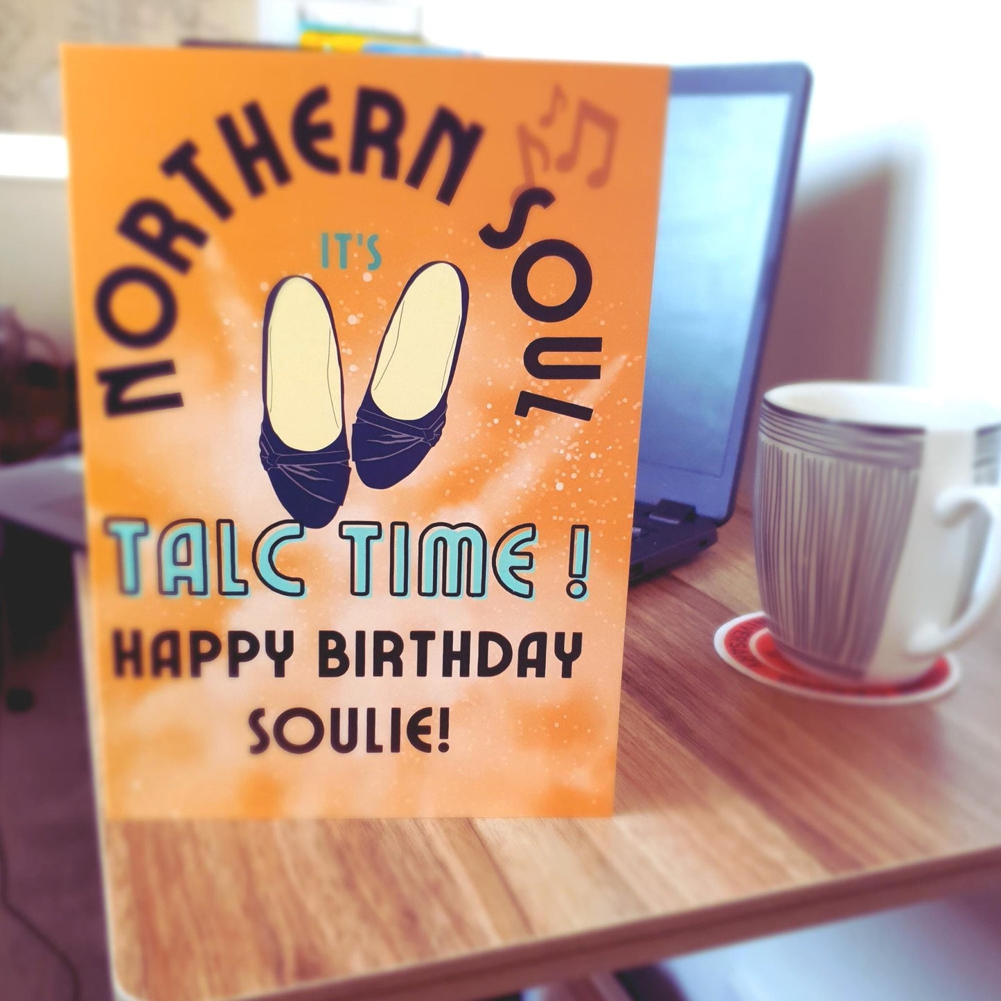 Greeting card with 'Northern Soul' design and text happy birthday soulie on a table with a laptop and mug.