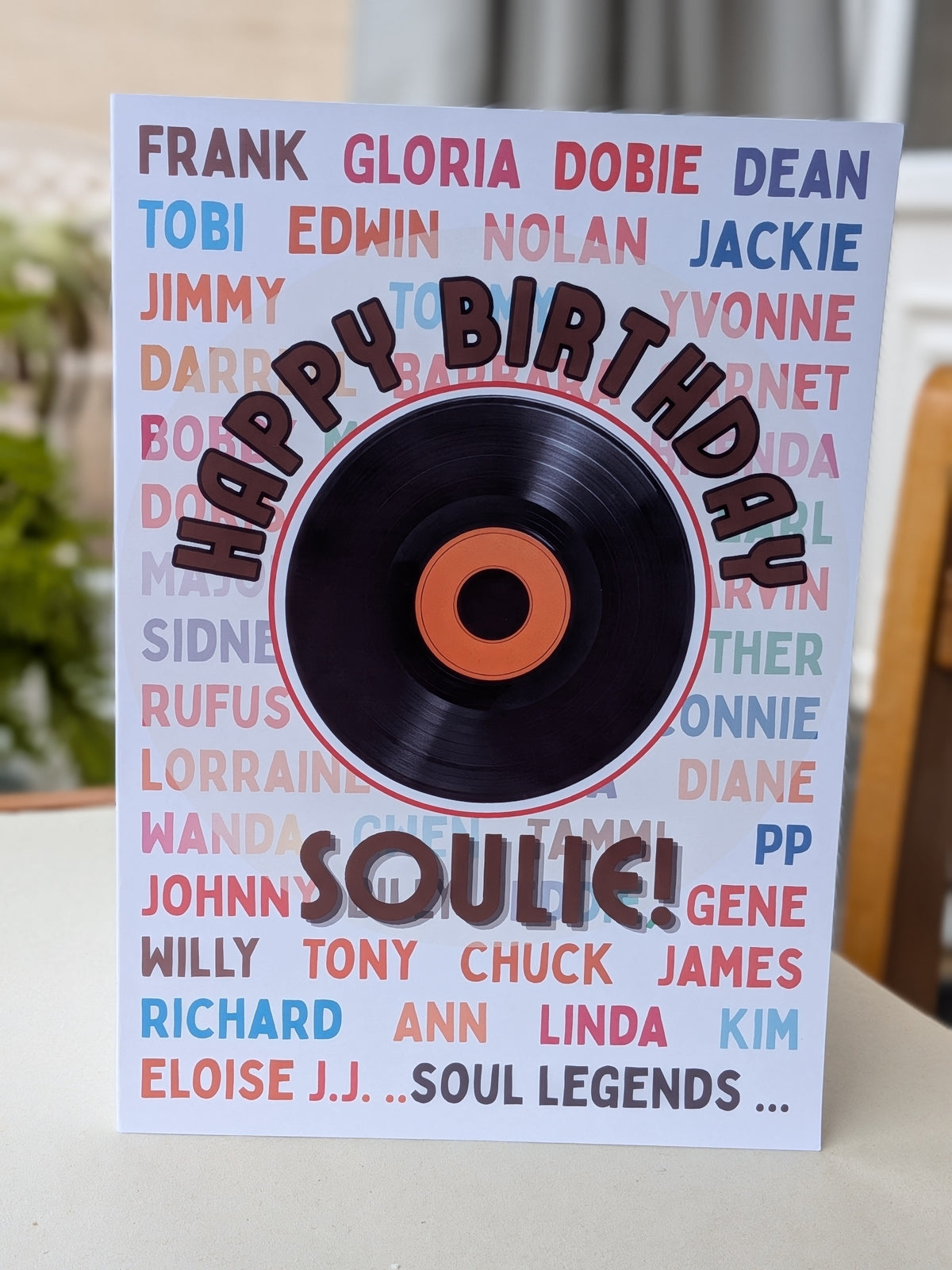 A'Happy Birthday Soulie!' greeting card featuring a black vinyl record graphic with an orange center label, surrounded by names of famous soul  artists in various colors on a white background.
