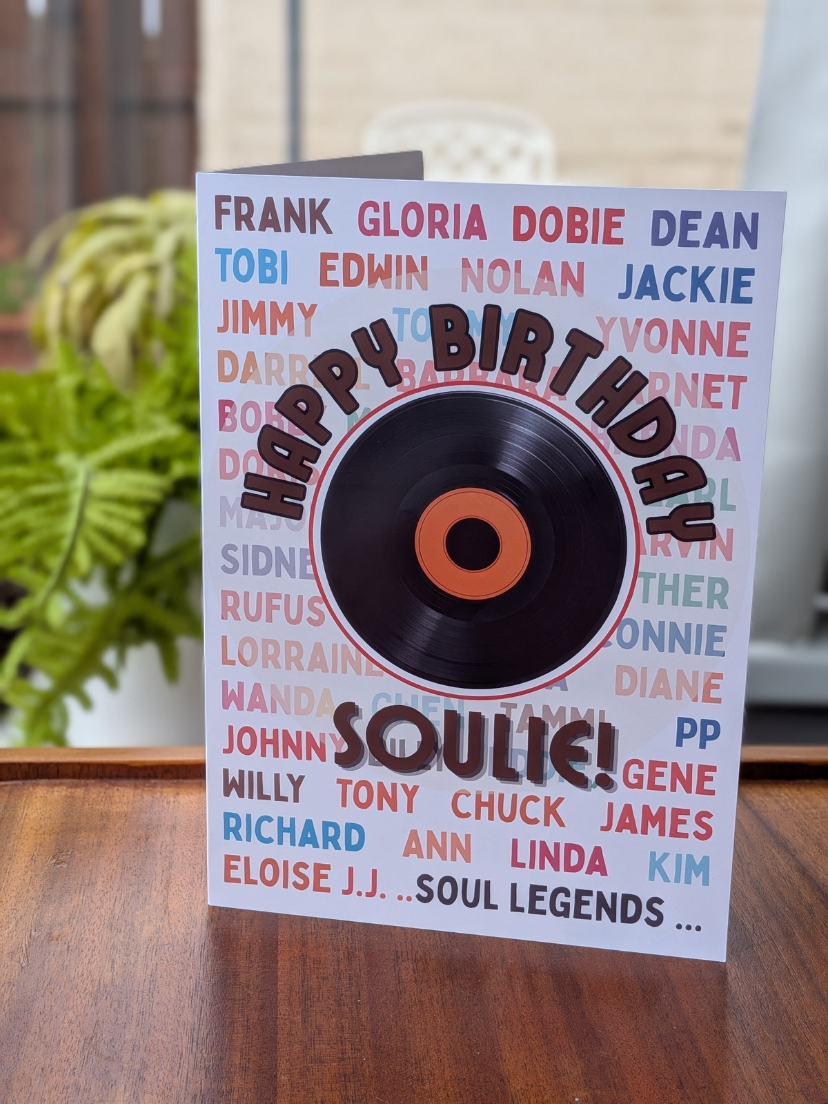 A birthday card featuring the words 'HAPPY BIRTHDAY SOULIE!' in bold lettering. The card is decorated with a background of colorful names in red, blue, and pink.