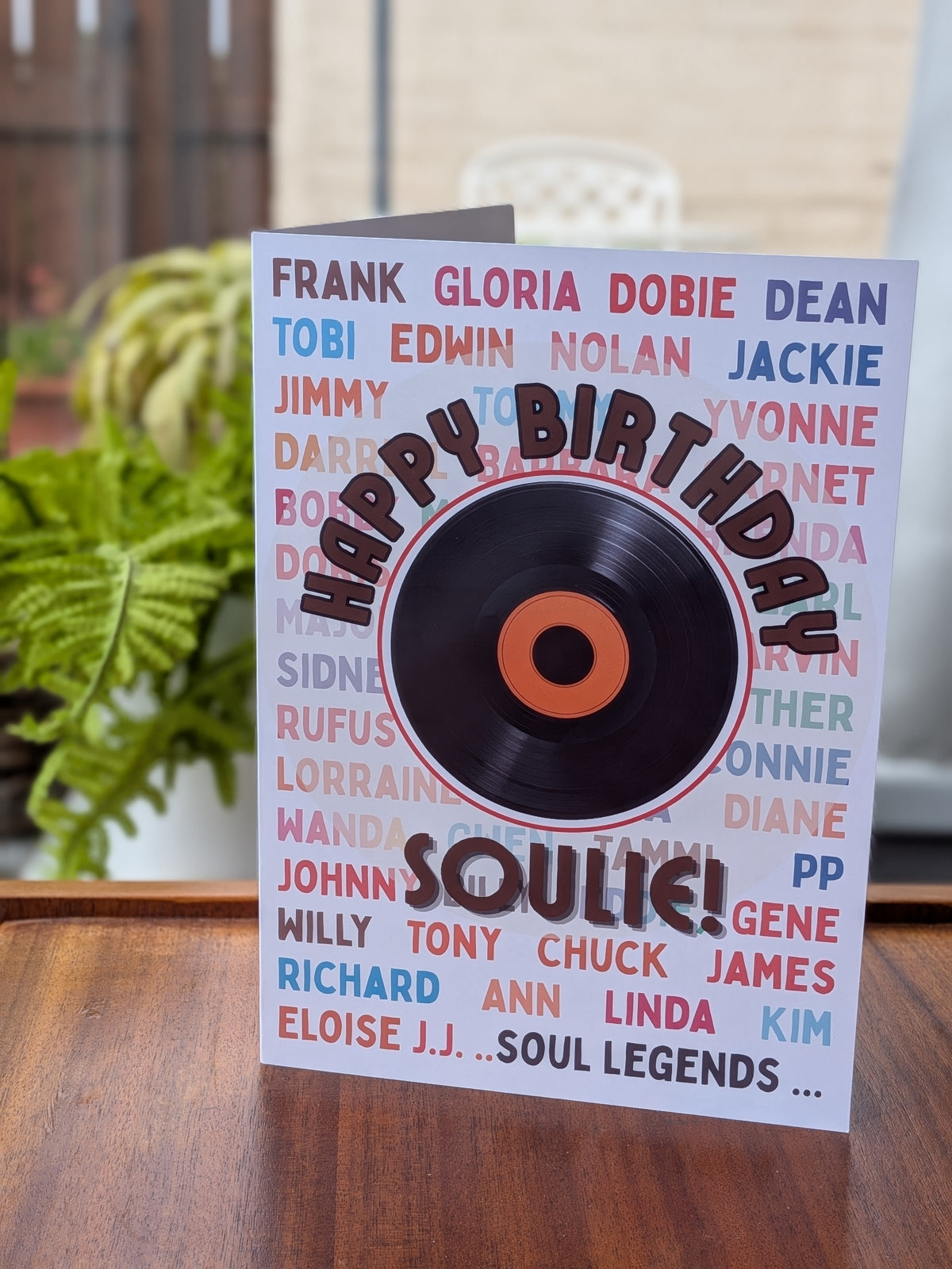 A birthday card featuring a vinyl record graphic in the center with the words 'HAPPY BIRTHDAY SOULIE!' in bold lettering. The card is decorated with a background of colorful names in red, blue, and pink.