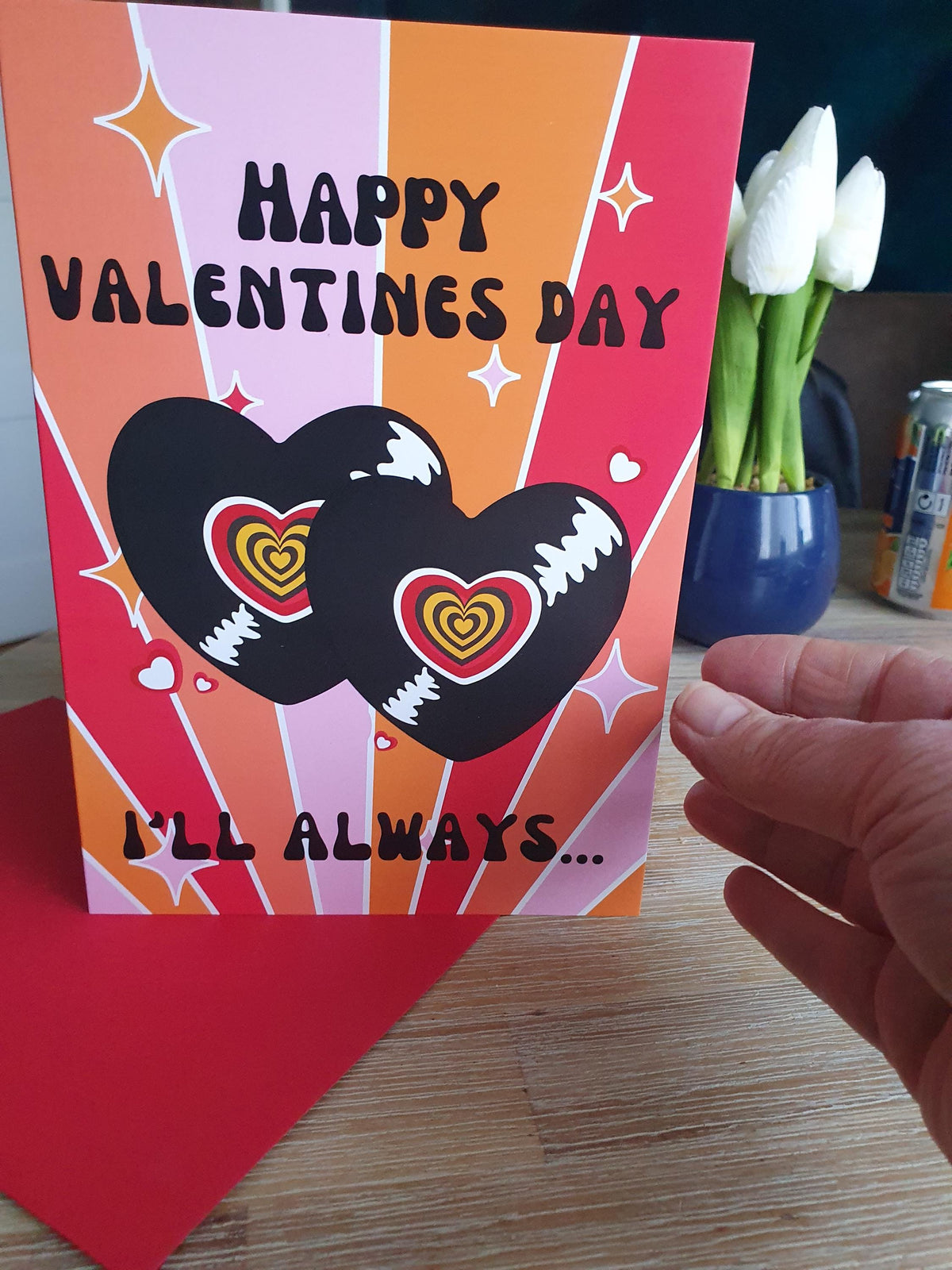 Valentine's Day card with hearts and 'Happy Valentine's Day' text, held by a hand.