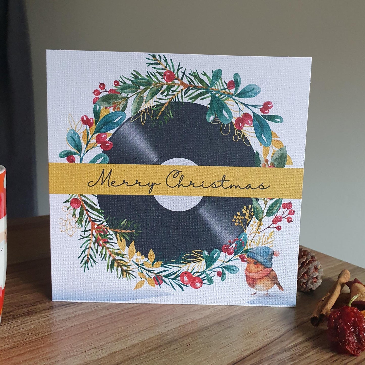 Christmas card with vinyl record and festive wreath on a wooden surface