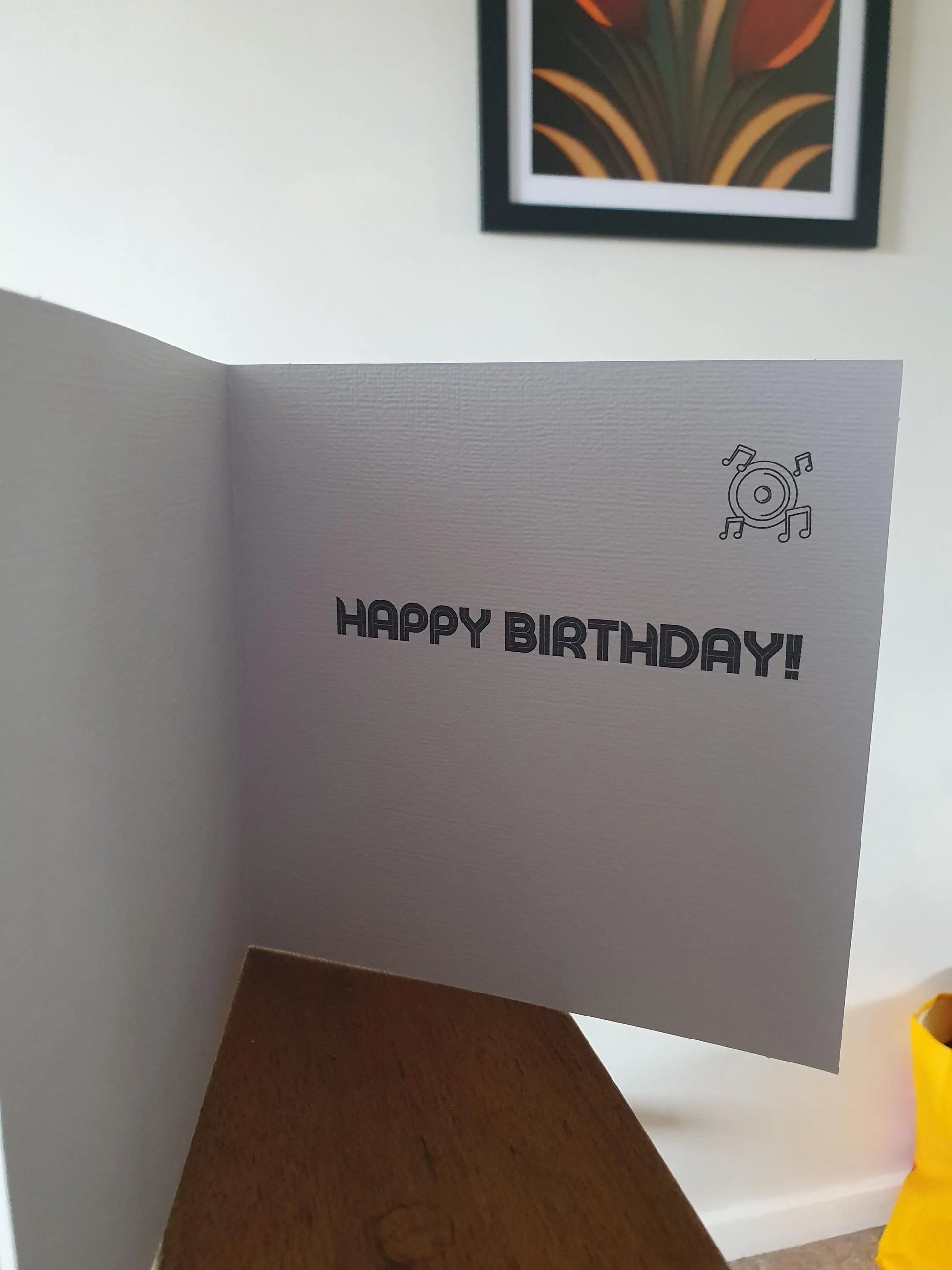 Inside of a birthday card with 'Happy Birthday!' text and a small record graphic on a white surface.