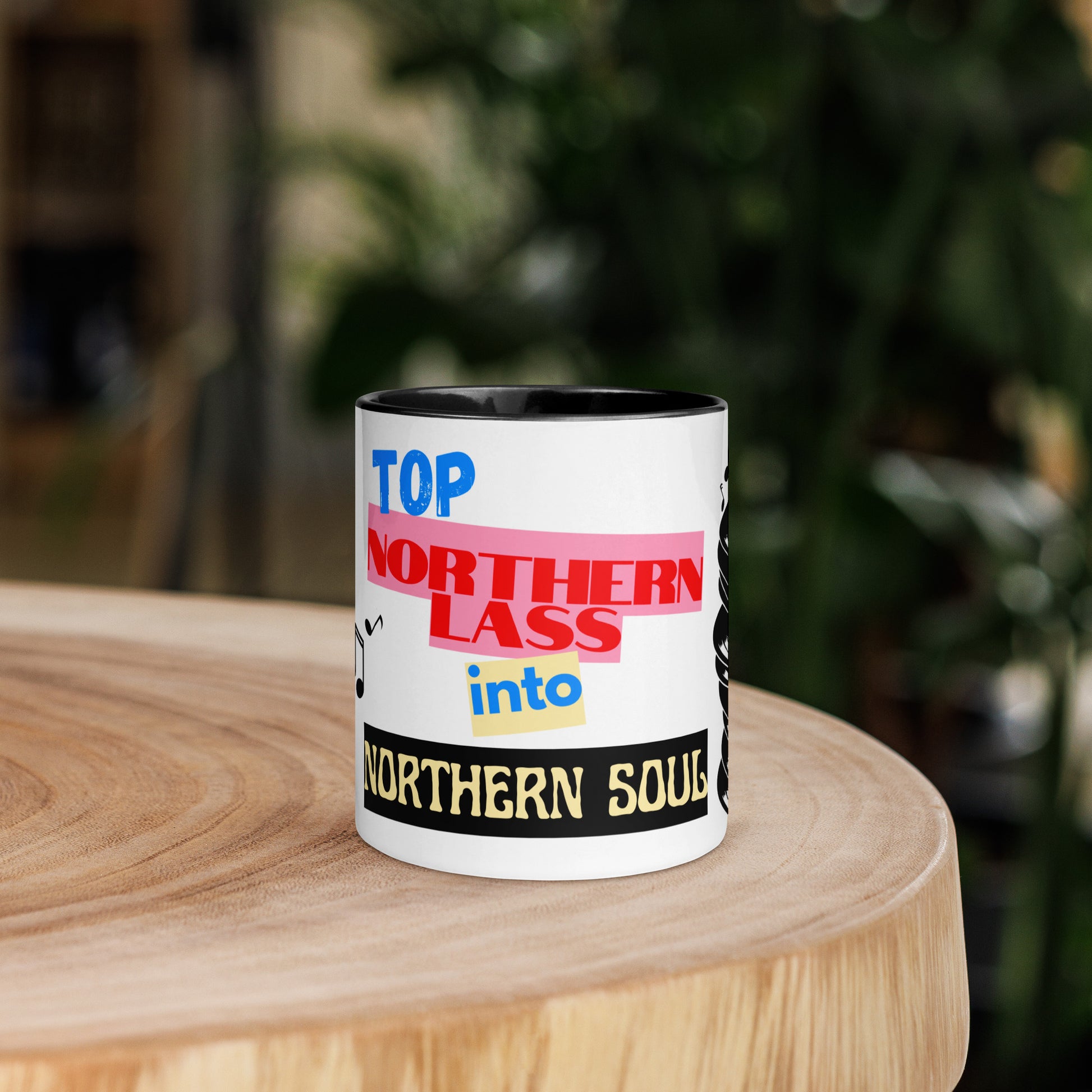 Mug with colorful text design stating northern lass into northern soul on a wooden surface