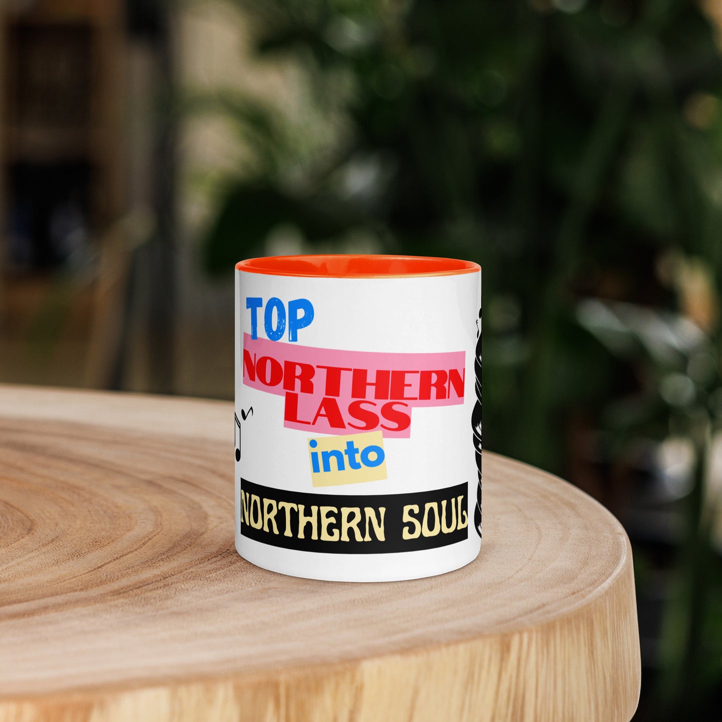 Mug with colorful text design stating northern lass into northern soul on a wooden surface