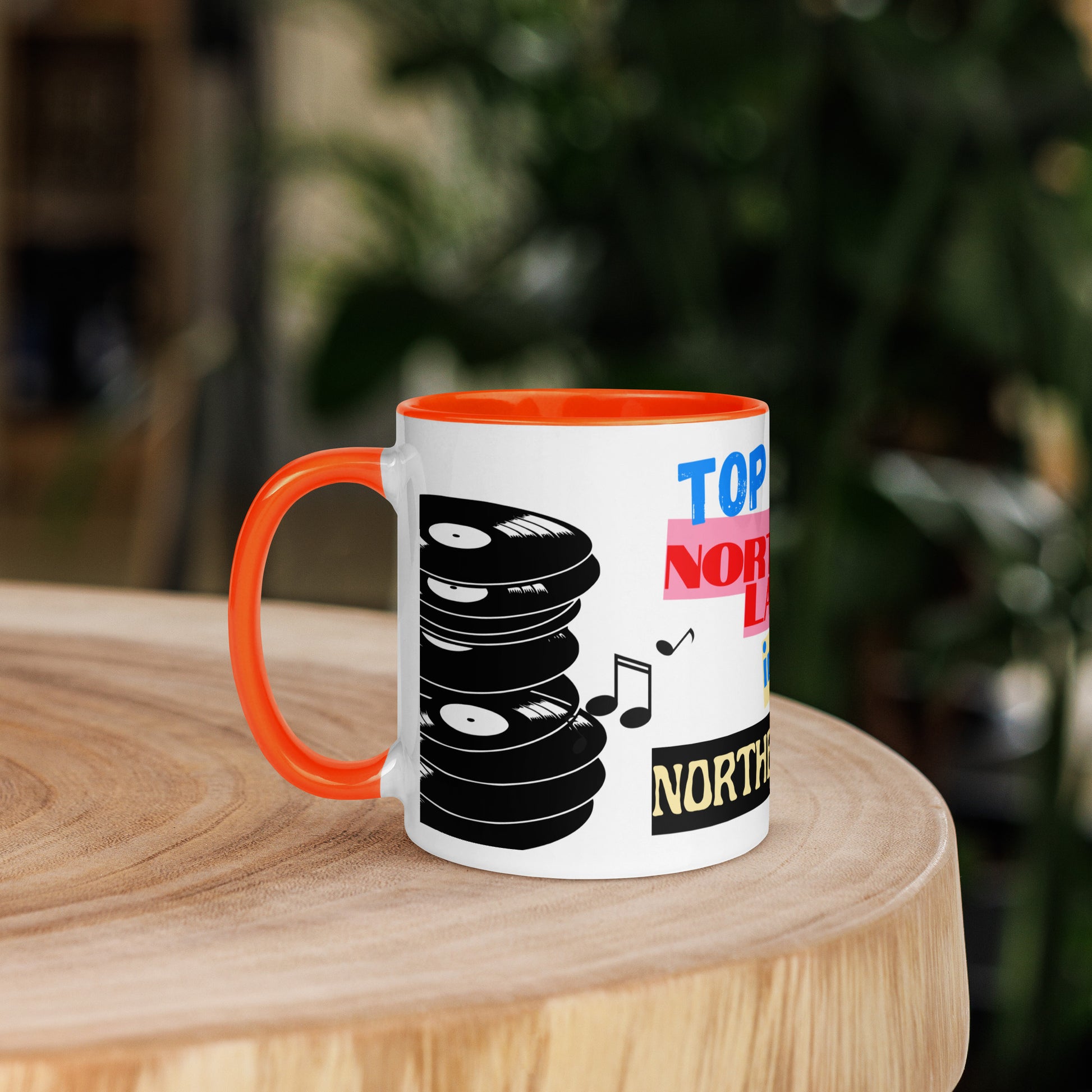 Mug with vinyl record design and text on a wooden surface with a blurred background