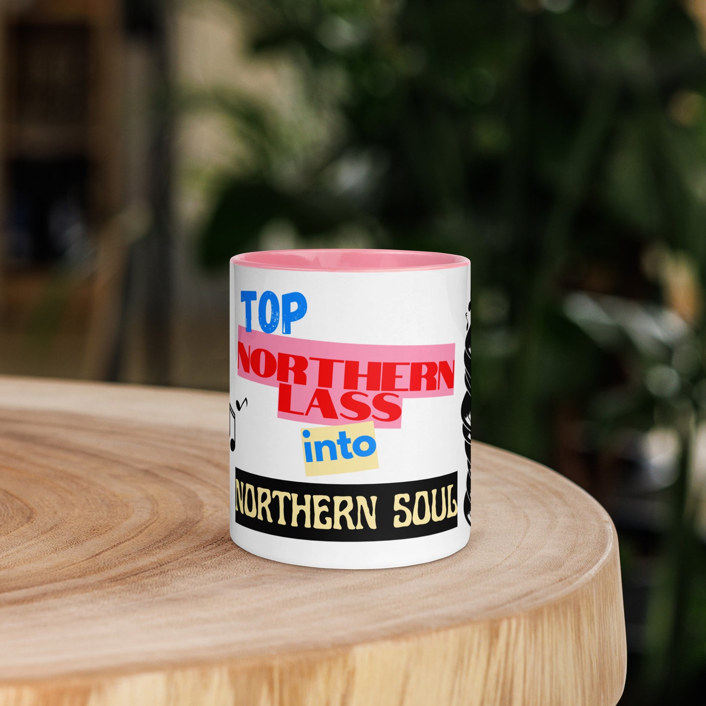 Mug with colorful text design stating northern lass into northern soul on a wooden surface